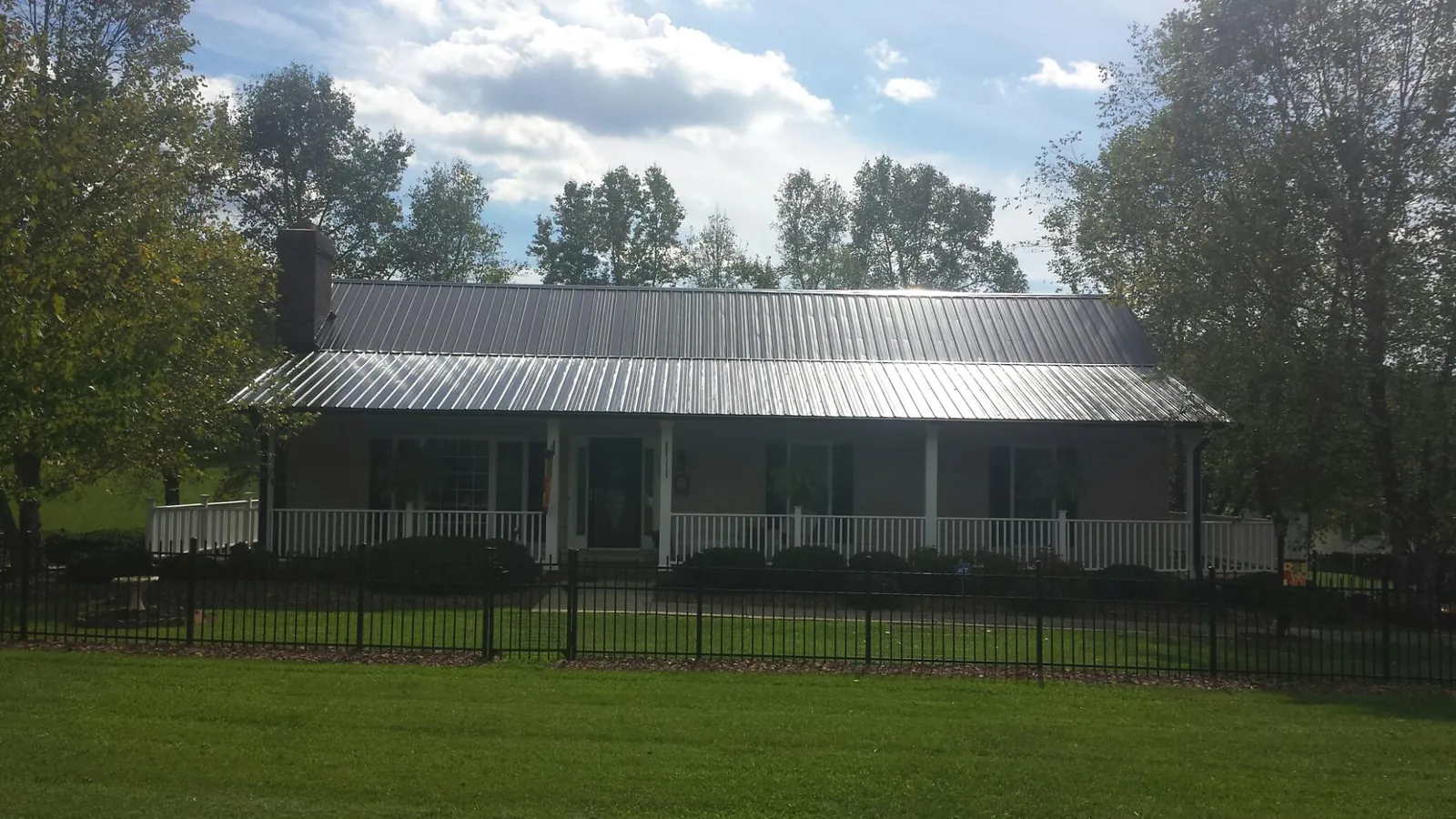 Gray metal roof on a brick ranch with a full width front porch — Gutter Guard Installation work by our crew in Plummer